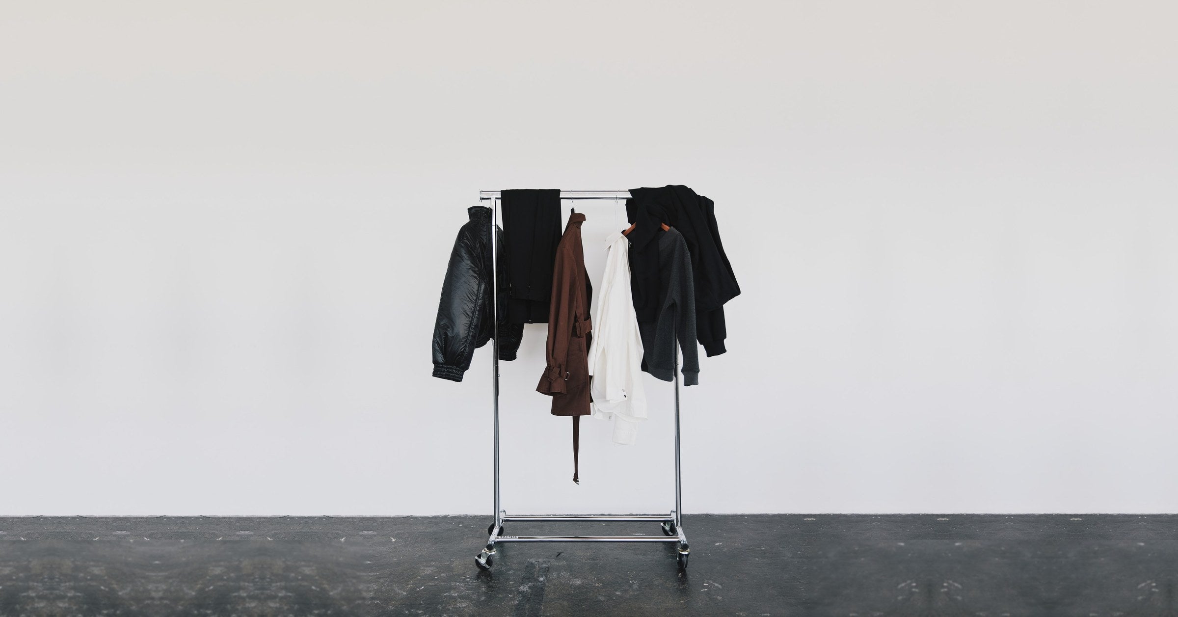 A rail of Stadion outerwear and tailoring in an empty white studio