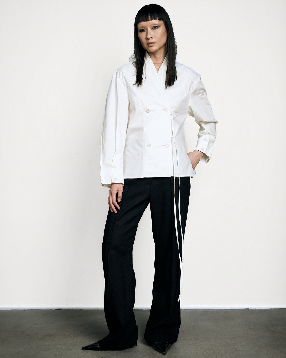 Woman wearing the Stadion Council shirt in ivory with black wide-leg trousers