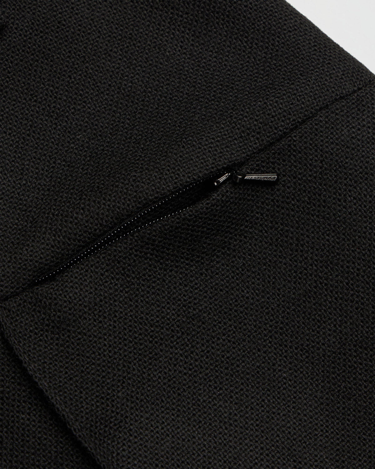 Detail of the concealed zip pocket on the textured black wool of the Ewan pillar trousers