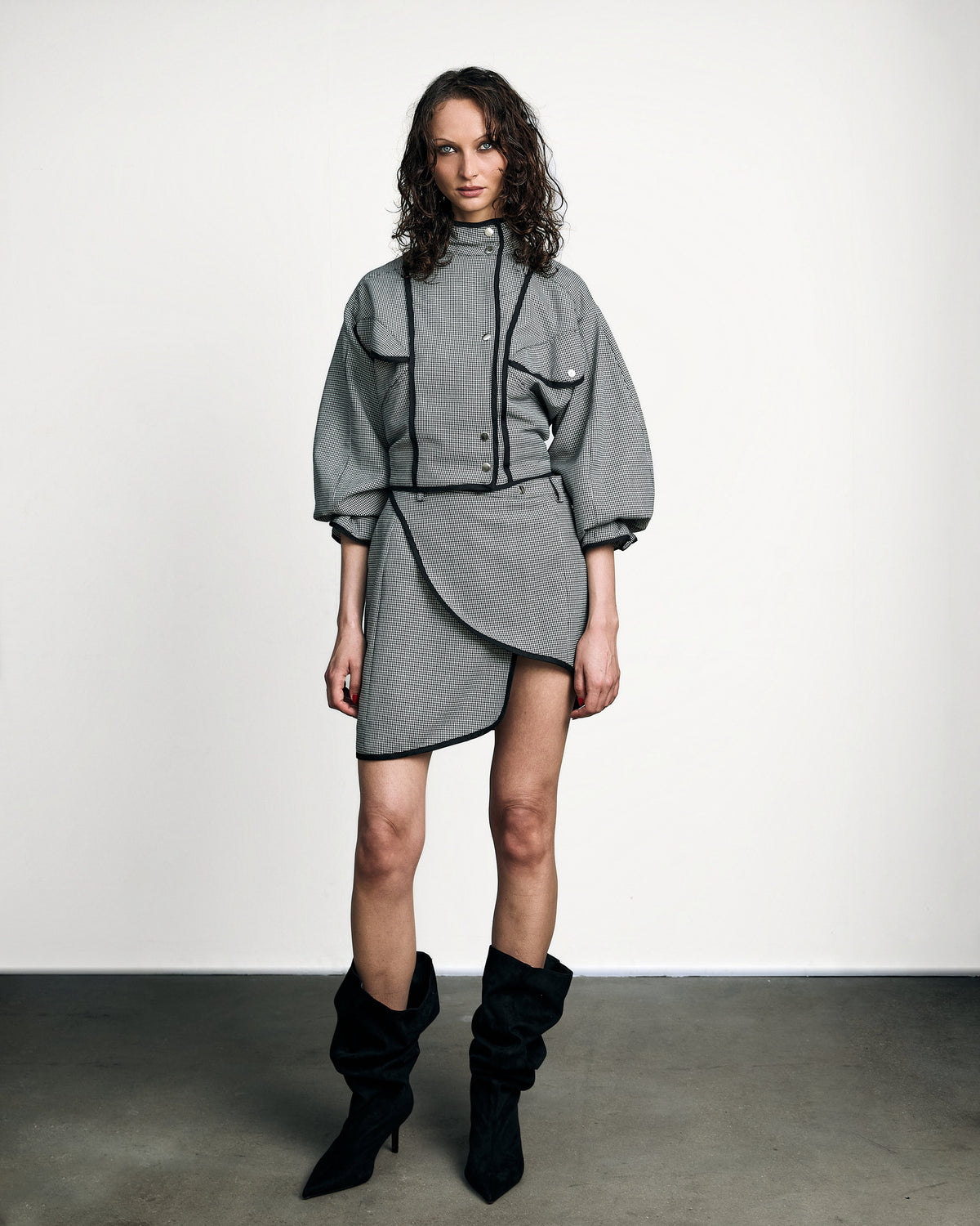 Woman wearing the Stadion Gibson coach jacket in houndstooth with the matching wrap skirt and black boots