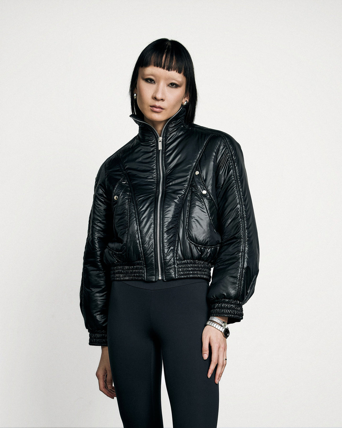 Woman wearing the Stadion Reserve bomber in black, worn over leggings