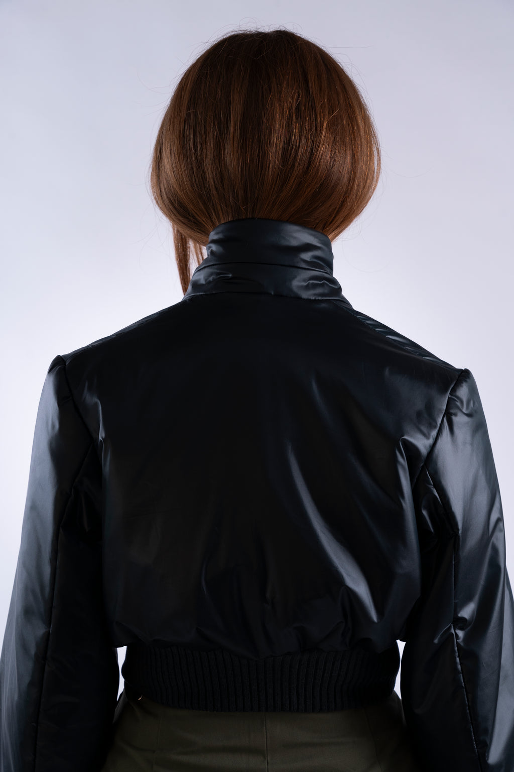 Flat lay back of Interface Bomber in midnight forest showing silhouette and panel design.